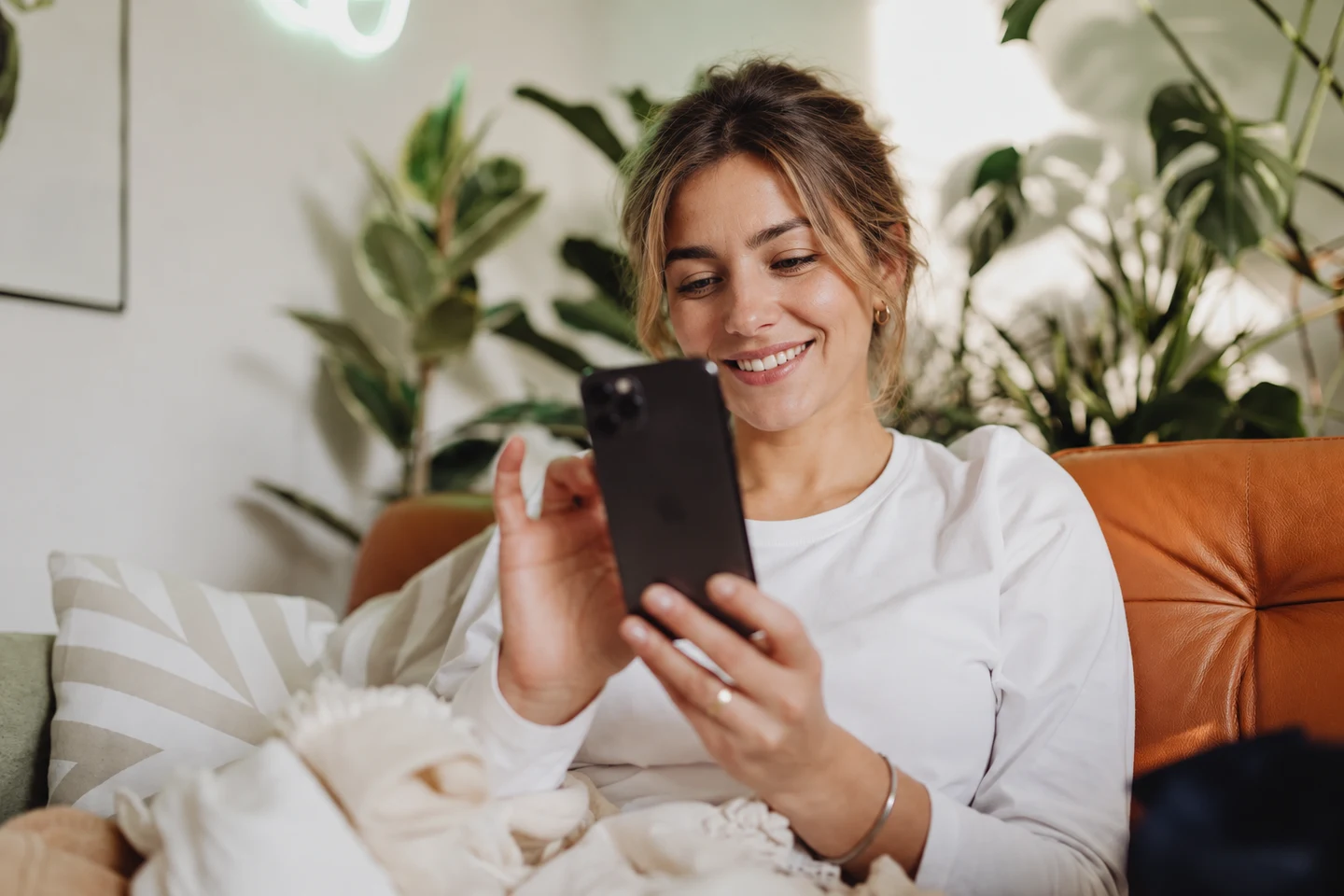 Evinde koltukta otururken telefon kullanan bir kişi